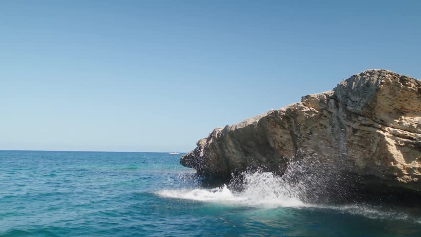 Two young women jumping off a cliff into water below on a bright sunny day
