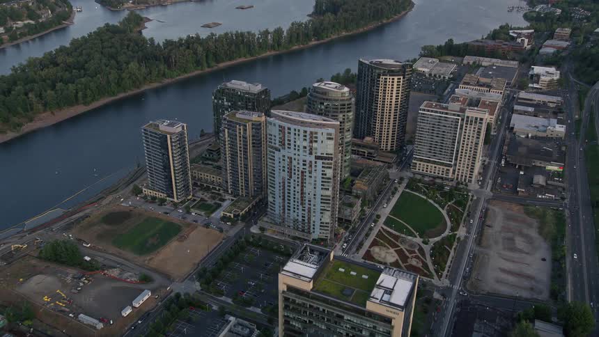 Approaching South Waterfront Portland Oregon at sunset showcasing high-rise buildings residential neighborhoods and a serene river flowing alongside the community