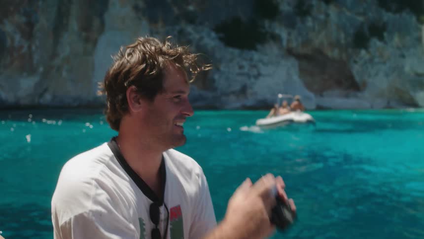 A male adult on white top smiling while taking photo shot on a floating boat