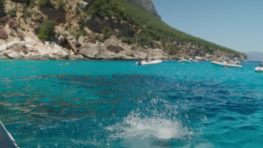 A woman jumps into the blue sea on a sunny day