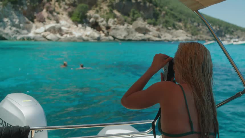 Woman photographing people swimming in the sea on a summer day