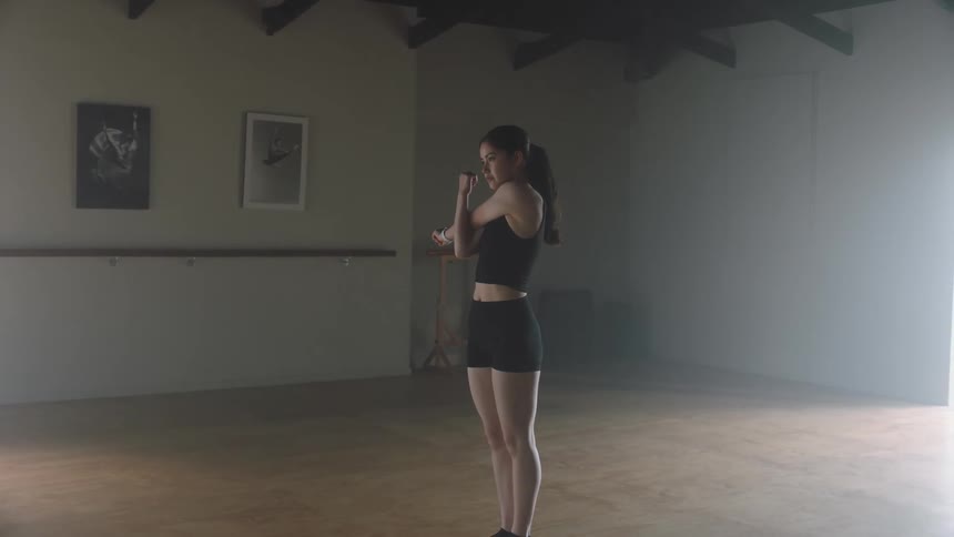 A young woman exercises in an empty room