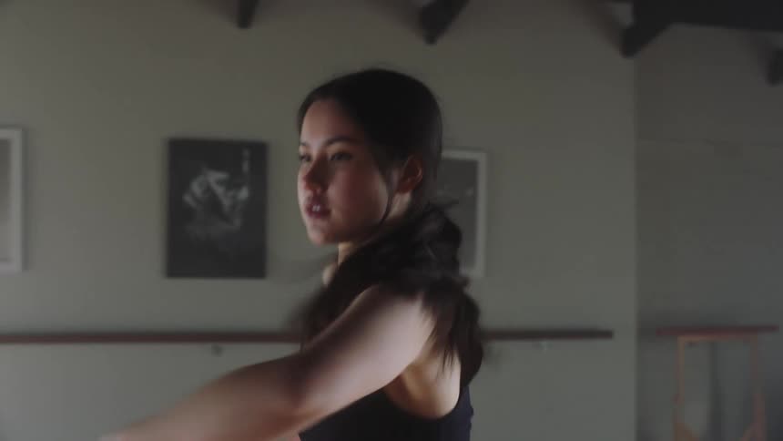 A woman wearing a black top dancing in a room with picture frames on the wall