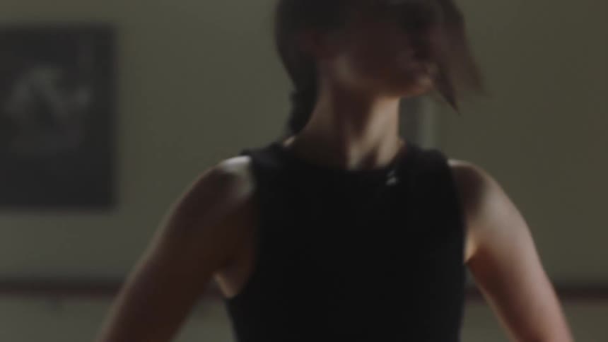 Female dancer practices routine alone in dance studio