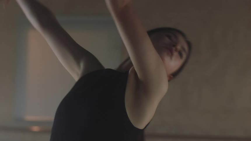 Young woman with her hair tied up dancing in an indoor room