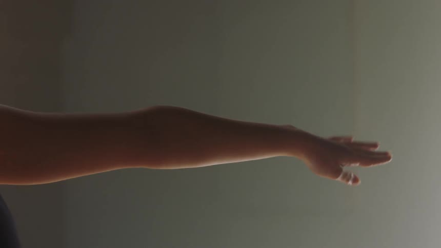 Darkhaired woman stretching indoors during day time