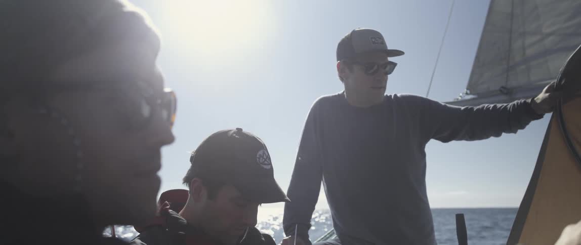 A man is speaking to other men sailing on a boat