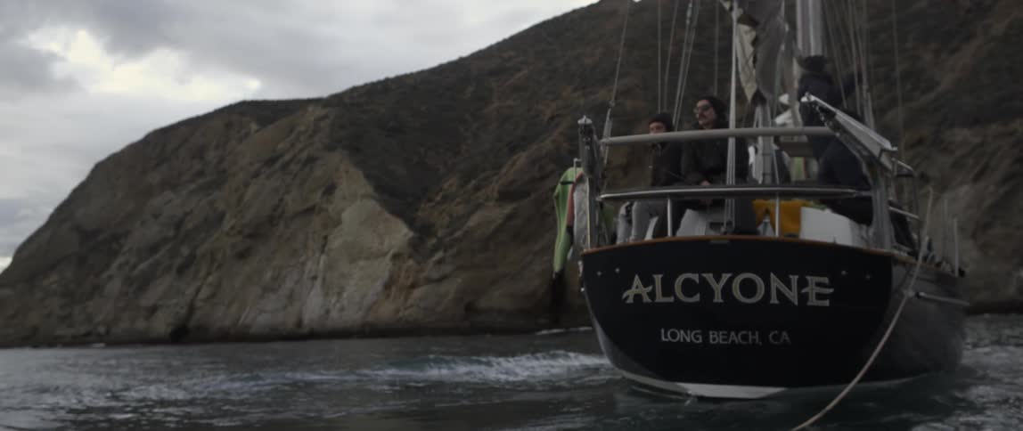 A boat is sailing in the water near a cliff