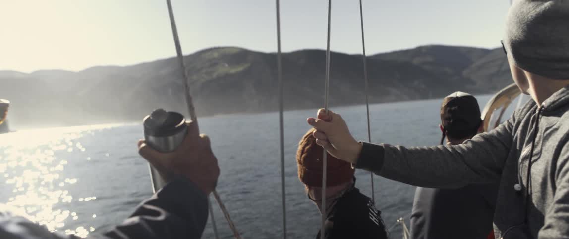 People are on a boat hanging onto ropes as it sails