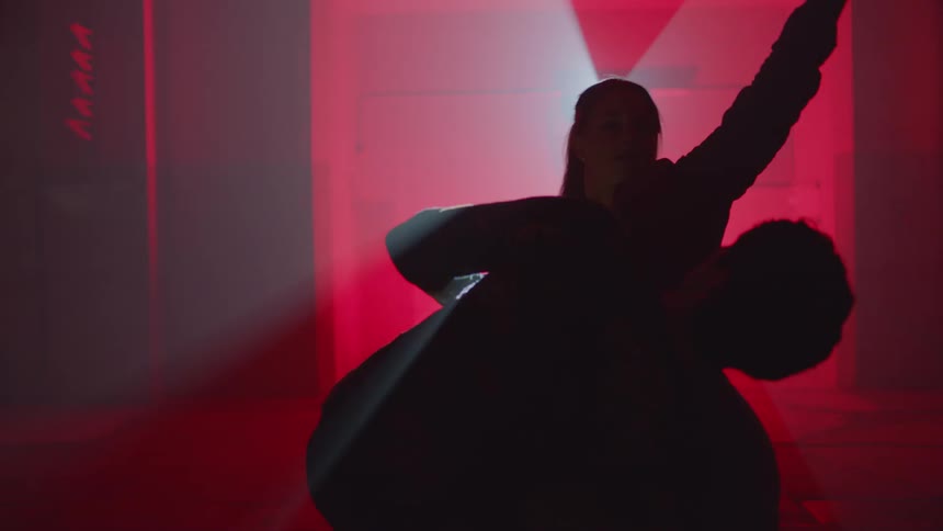 Man and woman facing each other dancing in a dimly lit location