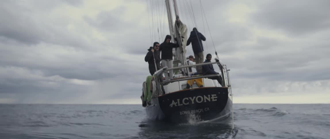A boat is traveling with people on it and it's sail down