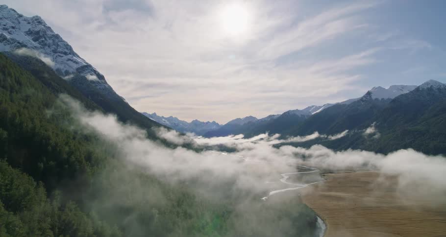 Aerial of low white clouds over a valley in the mountains