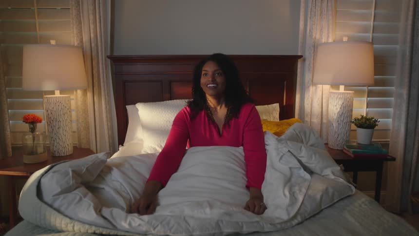 Happy young woman wakes up with energy in the bedroom
