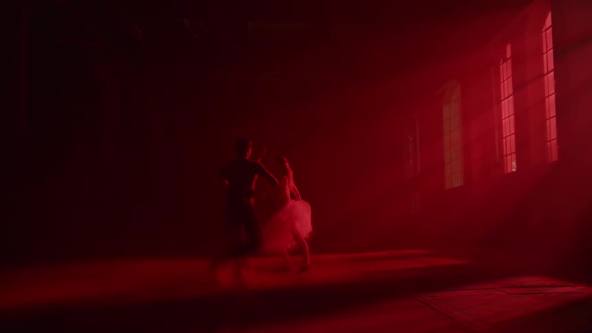 Man and woman performing ballet dancing under the red light