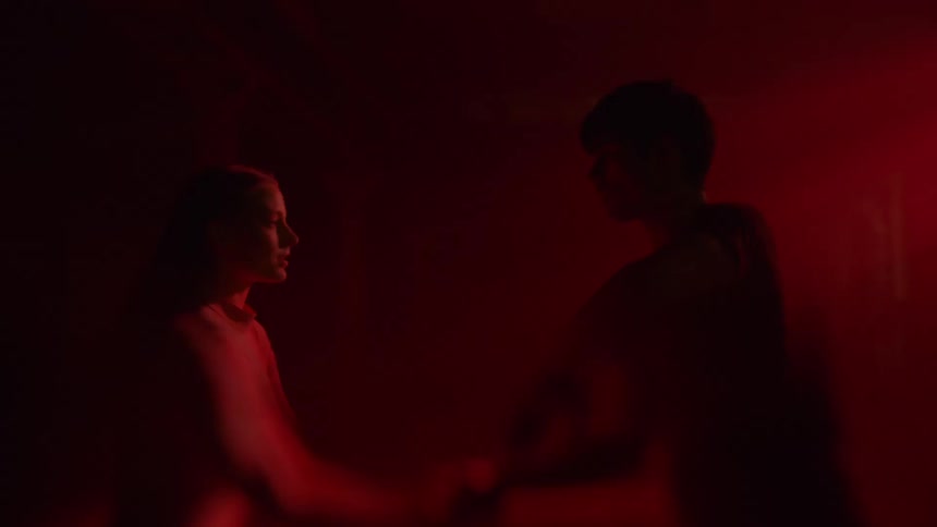 Two dancers performing indoors under red lights