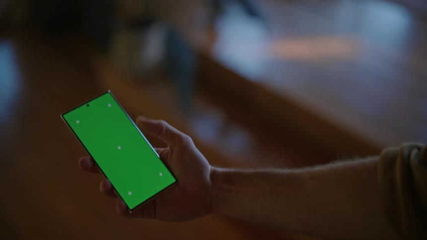 A person holding their phone with a focused expression as if tracking or monitoring an object