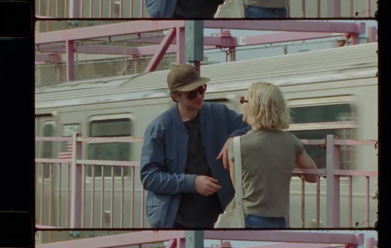 Young male and female chatting outdoors next to a train station during day time