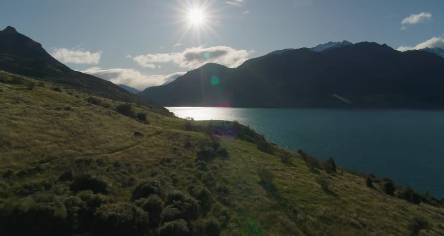 Man observing the natures horizon with sunlight lake and mountains around