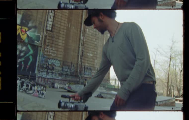 Man films skateboarder taking jump near graffiti wall mural
