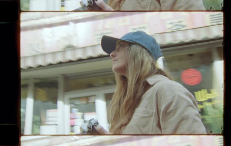 Woman wearing a cap outdoors taking pictures of a suburban neighborhood during day time