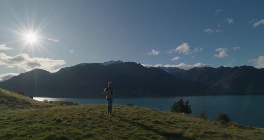 Man walking on land near a lake at sunset