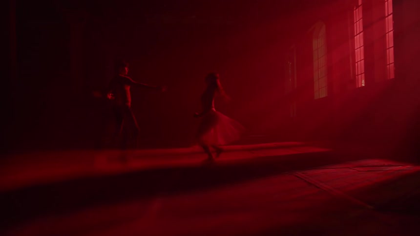 Man and woman doing ballet dance indoor under the red light