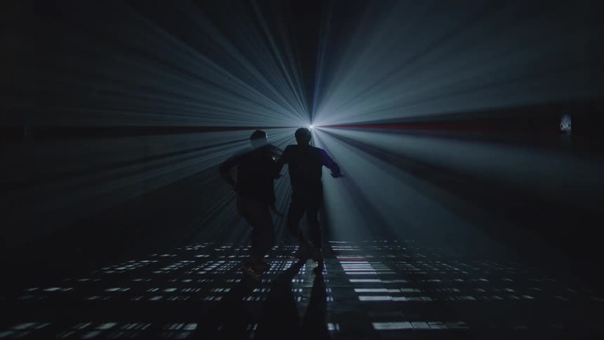 A man and a woman dancing in a darkened room with only a single point of light silhouetted