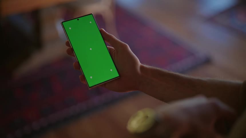 A person holding a cell phone with a green screen