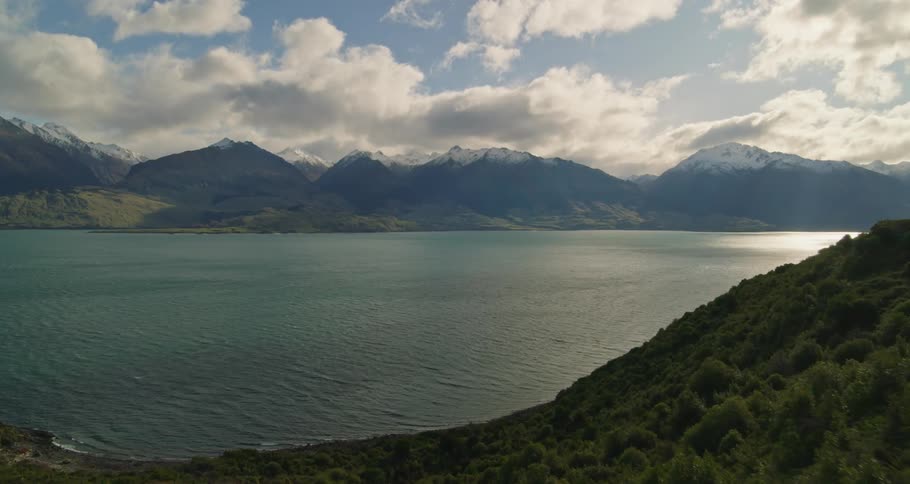 An aerial view of a river landscape with huge mountains in the background