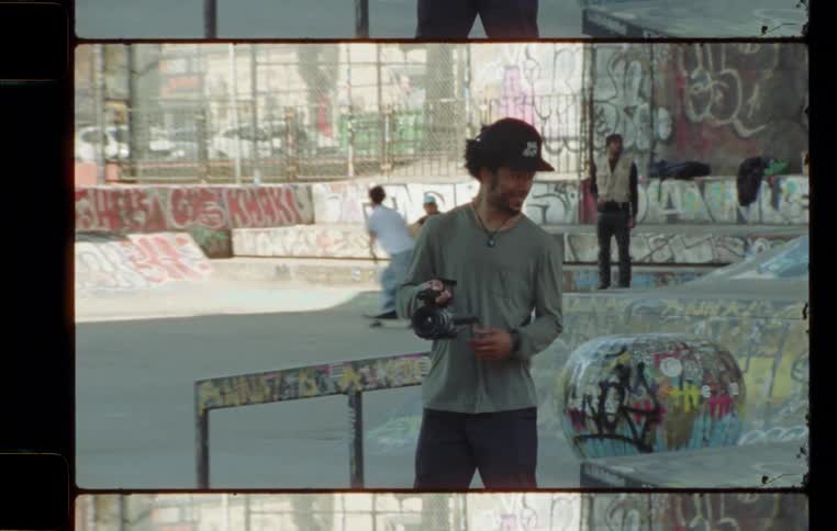A man with a video camera films a skater at a skate park