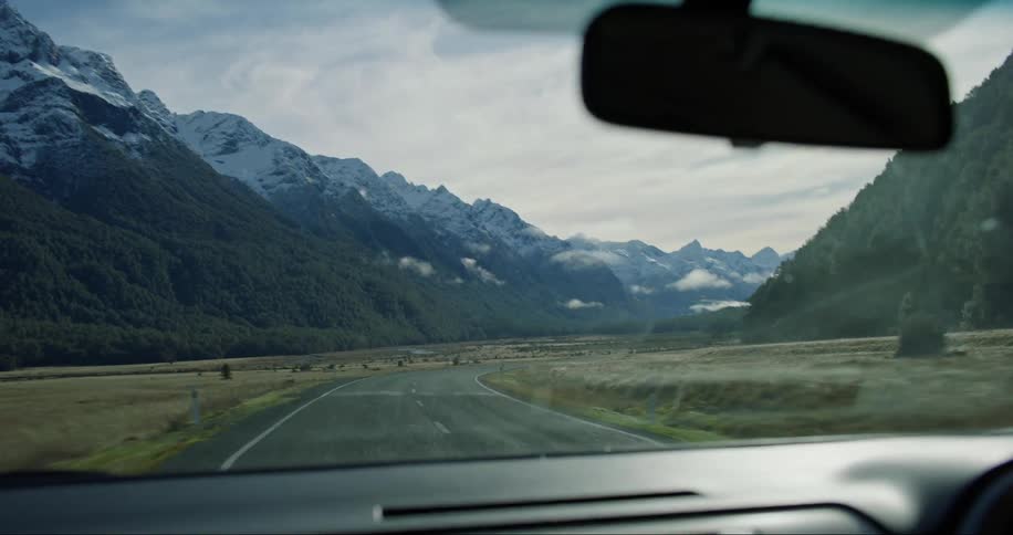 A car moving on a road in the middle of nature where there are mountains and hills around