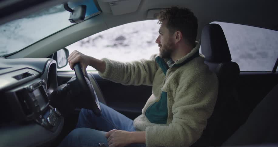 Man sitting on a car parked on a snowy countryside