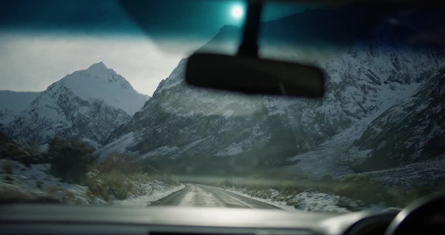 Car driving on a road close to a snowcovered mountain range