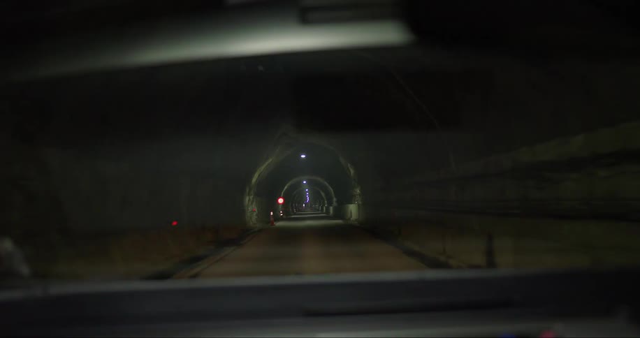 Car drives on a dark narrow tunnel