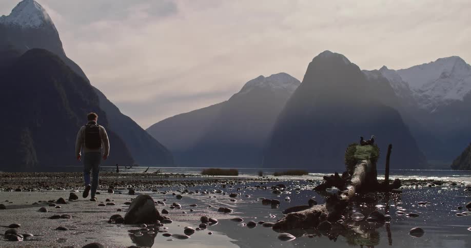 Man walking amidst nature with mountains and lake