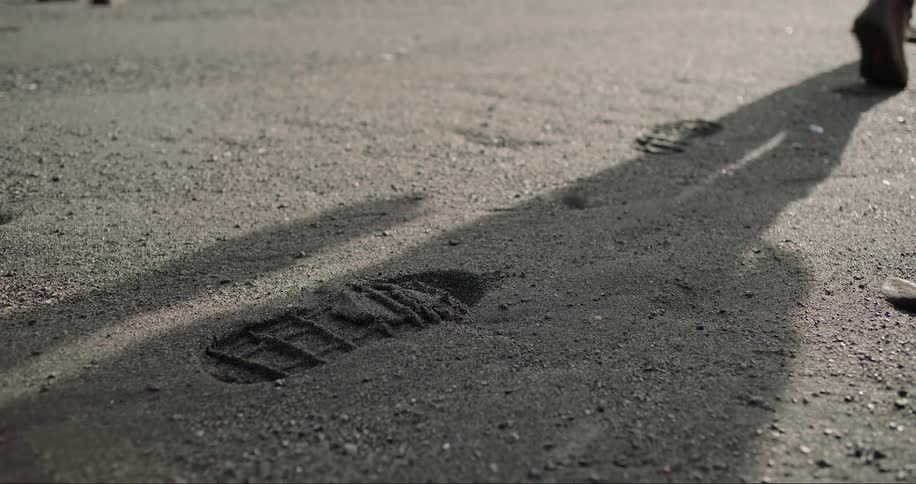 Person leaving footprints in wet sand during the day