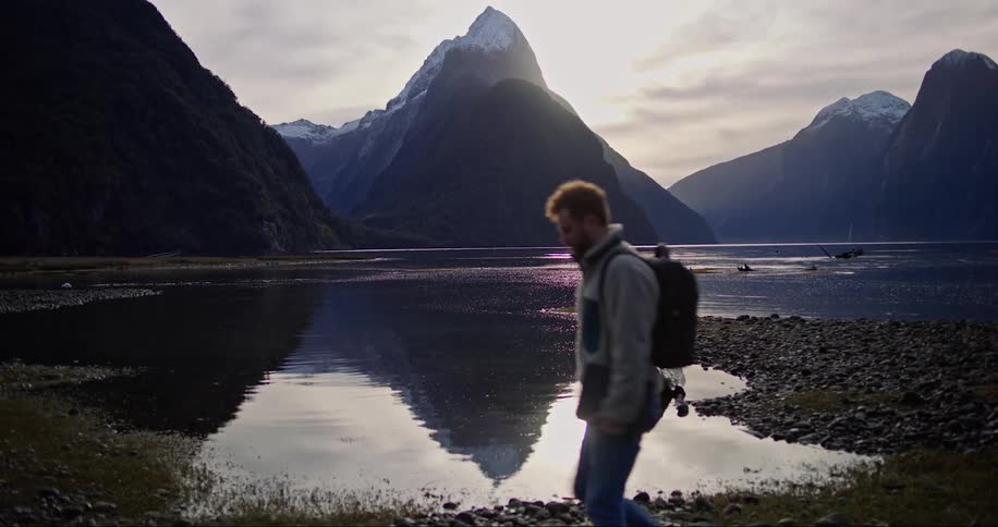A man hiking past the rocky river bank