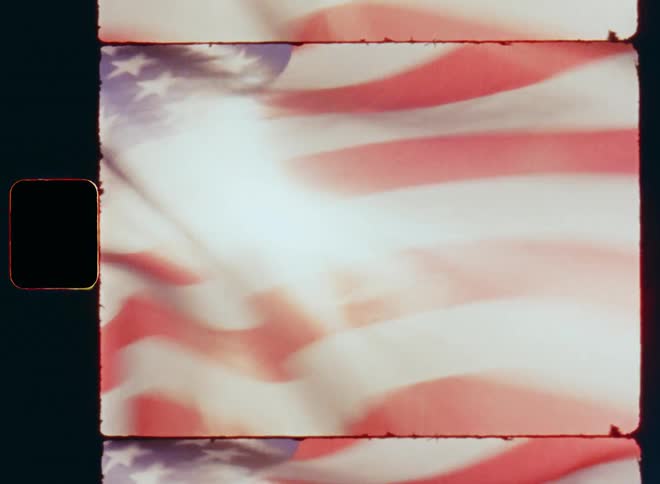 Looking up into a bright blue sky on a sunny summer day during July 4 party or celebration as the American flag is waving in a strong wind with proud Americana spirit expressing freedom and independence of the USA on old Super 8 closeup