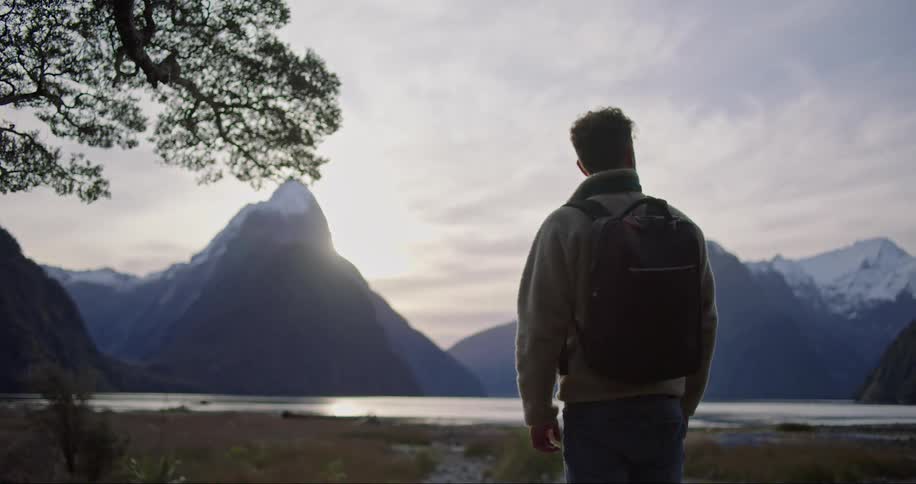 A man stands still looking at the landscape of mountains