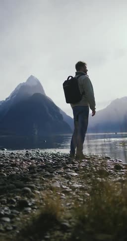 Man on the shore of the lake admiring the landscape with mountains