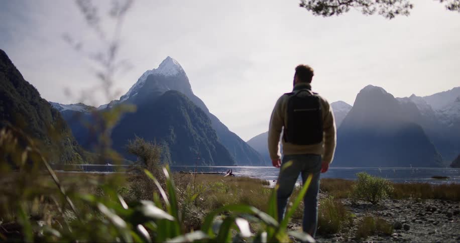 Man wearing backpack stands outdoors near mountains