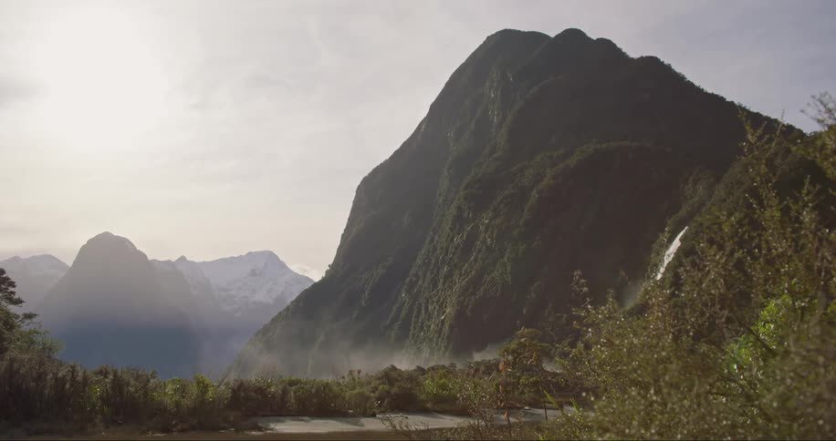A landscape of a hill and mountains with vegetation and forest and also a waterfall going down the mountains