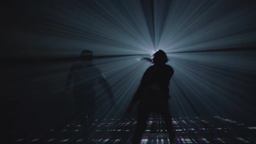 A man and a woman dancing together in the dark with a white and red light turning on and off in the room