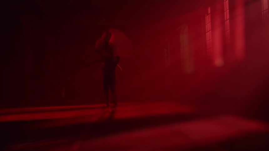 Ballerino lifts ballerina dancing in room with red lighting