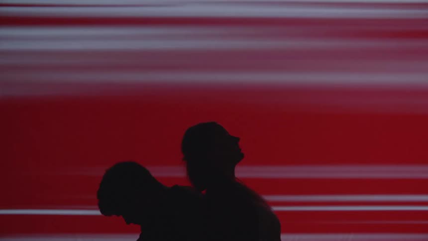 Two young adults in silhouette back to back