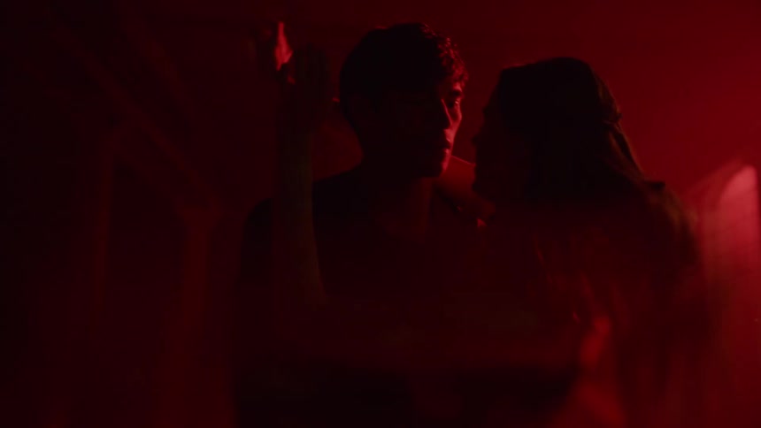 Dancers dance in a dark room with red lights