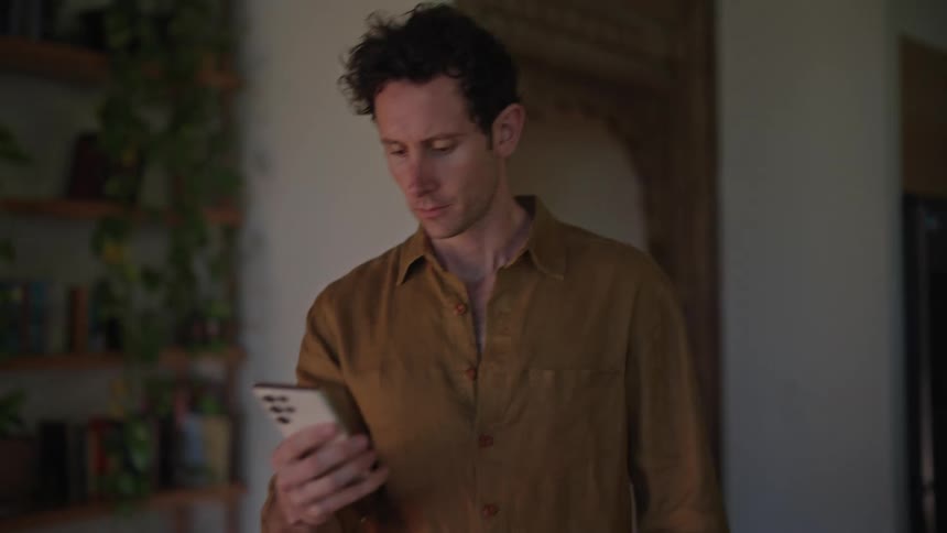 A man with a cell phone in his hand is walking with concentration