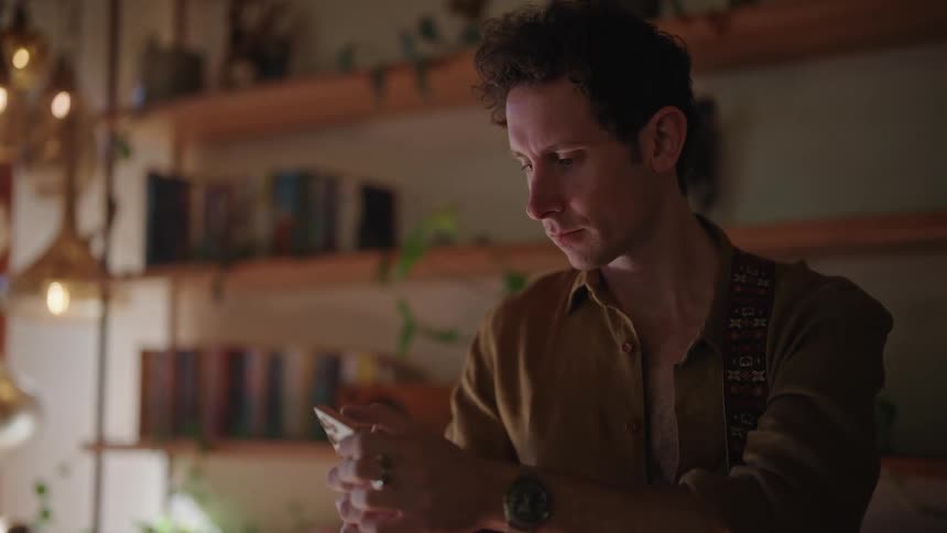 Man uses mobile device in room with long open shelves