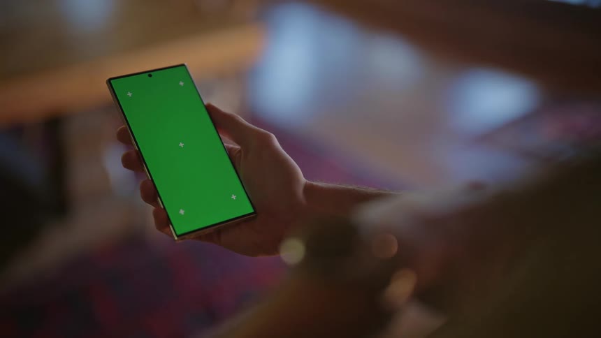 A mobile phone with a green screen in the hand of a person who swipes the screen