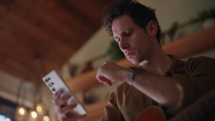 Young man looks at his phone with concern in the living room